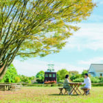 安曇野ちひろ公園のベンチでふたりが向かい合って座っている写真。