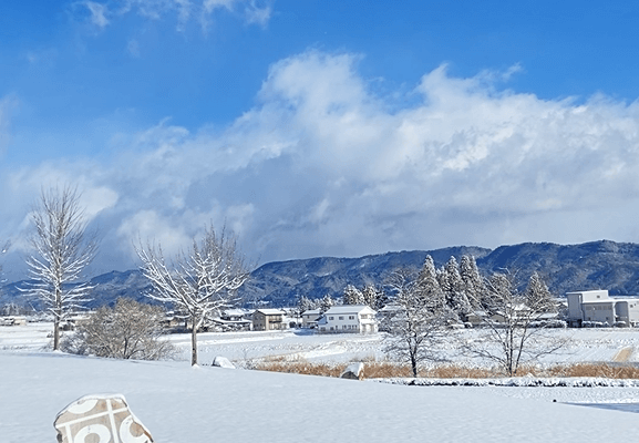 安曇野ちひろ公園の景色。雪が積もった地面の上に青空が広がっている。