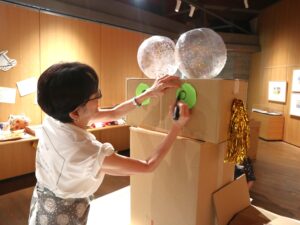 写真：2026/8/9撮影。ひみつきち迷路のシンボルタワーに顔を描く武田美穂さん。